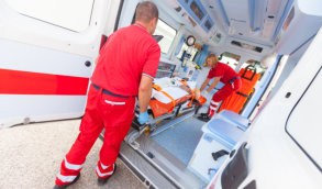 two medical personnels holding stretcher on a van