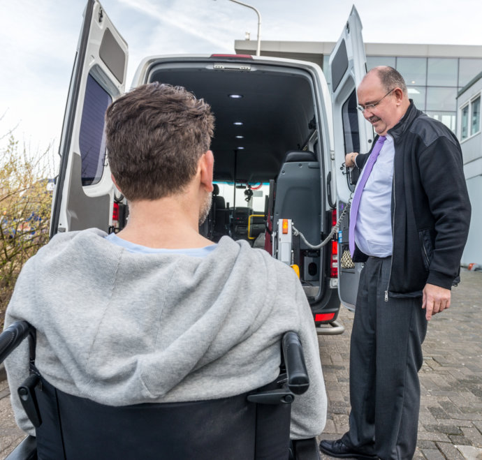 man assisting patient on a wheelchair to get on van