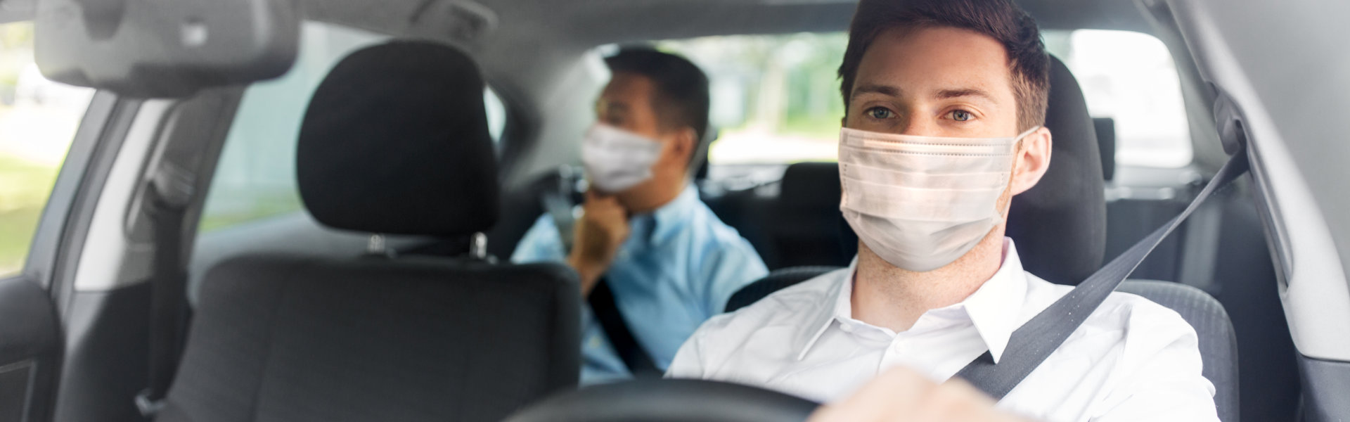 Health protection, safety and pandemic concept - male taxi driver wearing face protective medical mask driving car with passenger